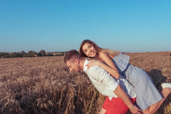 Jovem casal mulher e homem jogar no verão. Feliz regozijo divertido e rir. Romance em um campo de trigo no ar puro. Amor forte e relacionamentos felizes. Espaço livre para texto . — Fotografia de Stock