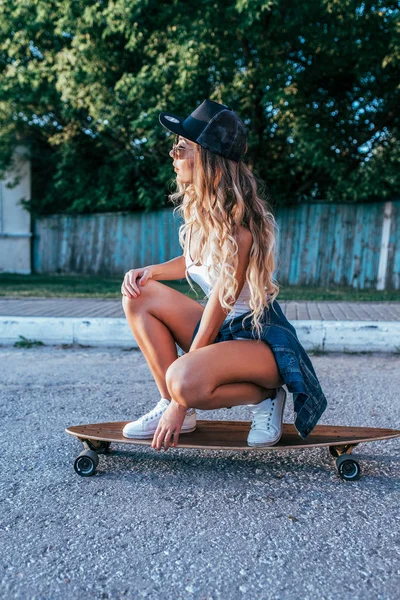 Seorang gadis dengan rambut panjang naik di musim panas di kota pada skateboard, longboard. Liburan akhir pekan, modis dan bergaya muda. Konsep gaya hidup, wanita fashion . — Stok Foto