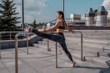 Kız germe, standları bölmelerini yaz City, spor giyim tozluk üst çeker. Isınma, jimnastik koşu spor yaptığını yapar. Kavram sağlıklı yaşam tarzı. Dövmeler tabaklanmış kadın deri kadın sporcu.