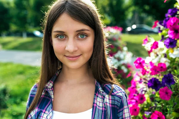 Schöne Schülerin 12-15 Jahre alt, steht im Sommer vor dem Hintergrund von Blumen. Nahaufnahme, Glücksgefühle, Freude, Lächeln. Freiraum für Text. — Stockfoto