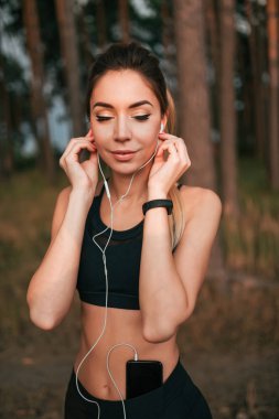 Güzel kız. Yaz parkında, ormanda. Dinlenme egzersiz temiz hava. Fitness egzersiz. Aktif yaşam tarzı doğası. Müzik kulaklıkları dinliyorum, koşu sabahı. Duygular zevk zevk mutluluk ve sevinç.