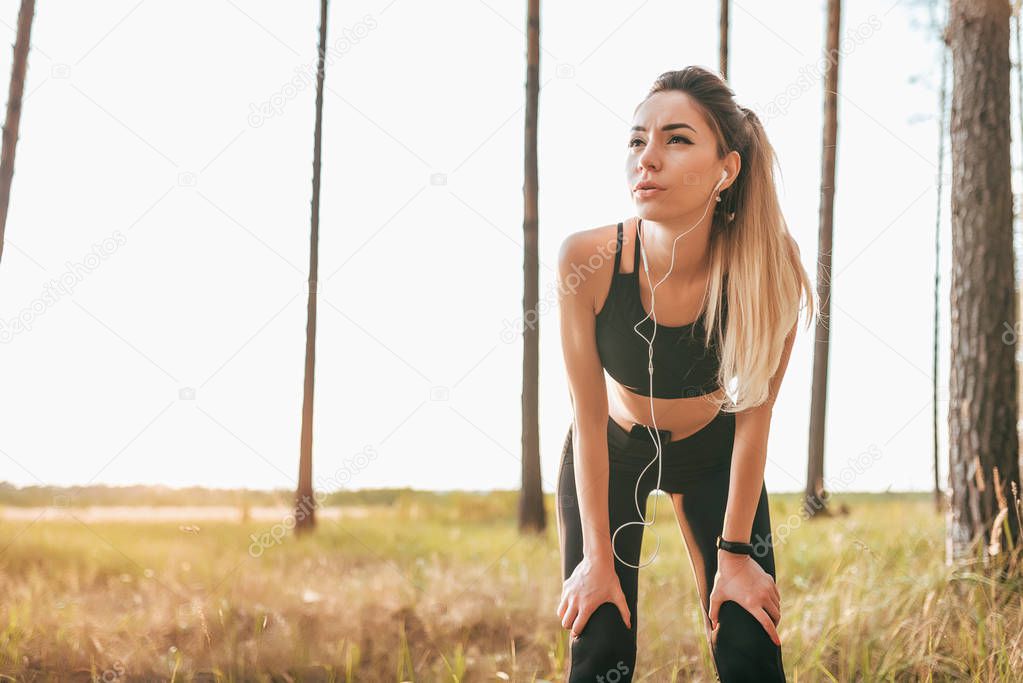 Girl sportswear leggings top. Rest doing fitness workout. Active lifestyle nature. In summer park, forest. Listening music headphones, shortness breath jogging morning evening. Free space for text.