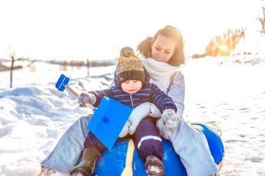 3 yaşında küçük bir anne ve oğul. Kış borularında, bir tepenin üstünde kar altında at sürersin. Kış tatilinde tatiller. Duygular neşe gülümsemesi. Sıcak kıyafetler ve eldivenler, bebek küreği..