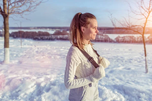 Tyttö lämpimässä villapaita ja haalarit talvella raitista ilmaa. Taustapuita lumi ja ajelehtii. Vapaa tila tekstille. Käsite levätä keinona talvella . — kuvapankkivalokuva
