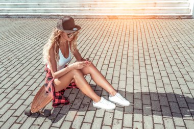 Kız şehirde kaykay yaz oturur. Kaykay, uzun tahta. Telefonda mesaj yazar, sosyal ağları okur, interneti internetten okur. Tabaklanmış cilt uzun saçlıdır. Konsept moda yaşam tarzı gençler.