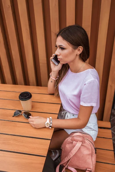 Mujer en el verano sentada en la cafetería de la ciudad. Gafas de sol, una taza de té de café, llamada telefónica en línea, almuerzo, almuerzo, merienda. Señora de los negocios después del trabajo en un restaurante . — Foto de Stock