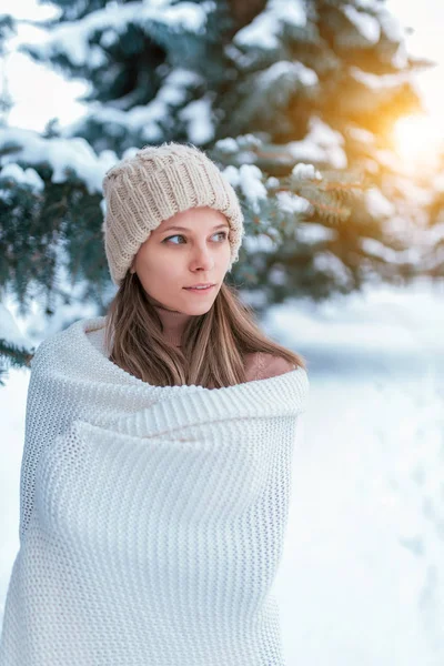Een vrouw in een witte Plaid, in de winter op straat, achtergrond sneeuw Drifts kerstboom. Gelukkige glimlach. Het concept van openluchtrecreatie in het weekend, vakantie in het Resort. Warme muts lang haar. — Stockfoto