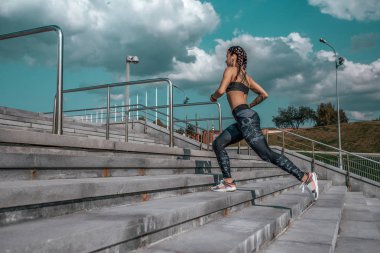 Kız atlet kadın, merdivenlerde, yaz şehirde, boş alan, fitness egzersiz, gün ve sabah çalışır. Spor kıyafetler, tozluklar en iyi spor ayakkabılar. Aktif yaşam tarzı, motivasyon gücü. İnternet uygulaması, müzik.