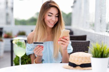 Kadın yazlık kafe, kredi kartı telefonu, ödemeler, siparişler, para hesabı. Temassız ödeme, kahvaltı, öğle yemeği. Çevrimiçi uygulama parolayı girin. Mutlu gülüşler, duygular neşe.