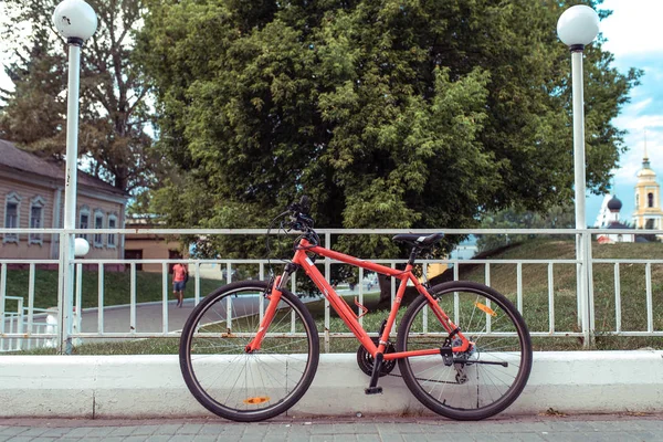 도시에서 여름에 주차 자전거, 바퀴와 빨간 검은 색 스티어링 휠과 의자. 램프 배경 나무 울타리 기둥입니다. 텍스트의 여유 공간입니다. 공원에서 도시 주말에 주차의 개념. — 스톡 사진