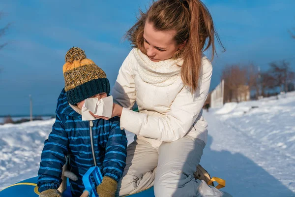 Mutter Frau wischt ihrem Kind die Nase Junge 3 Jahre alt, im Winter draußen, Husten Rotz, Schnupfen und Grippe, an einem kalten Wintertag. Zelten am Wochenende im Urlaub. — Stockfoto