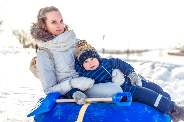 Мама с мальчиком 3 года, зимой в паре на холме, надувная игрушка для катания на лыжах, свежий воздух. Праздничные выходные городской парк. Играть весело смеяться смеяться . — стоковое фото