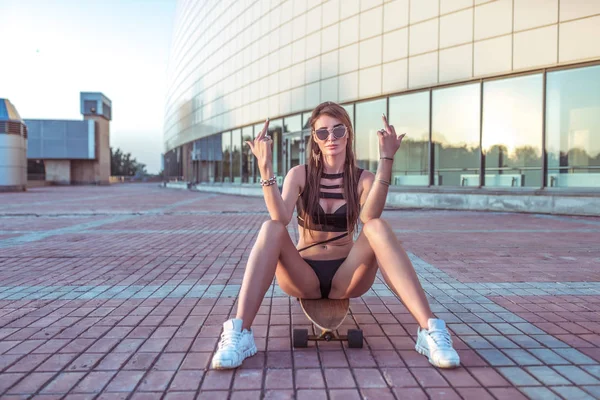 Beautiful young girl summer city, shows middle finger, gesture is no stop, went from here on a board. Fashion lifestyle youth. Concept enough, back off, good night, no, not interesting, got out. — Stock Photo, Image