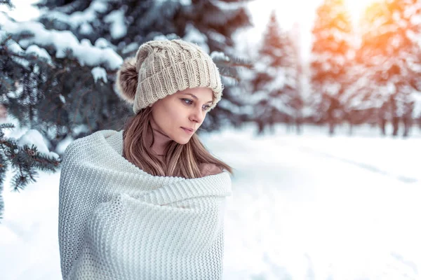 Closeup portrait winter woman background snow and Christmas trees. White warm winter hat, large long woolen plaid sweater. Rest weekend in nature, in cold weather at resort. Free space for text. — Stock Photo, Image