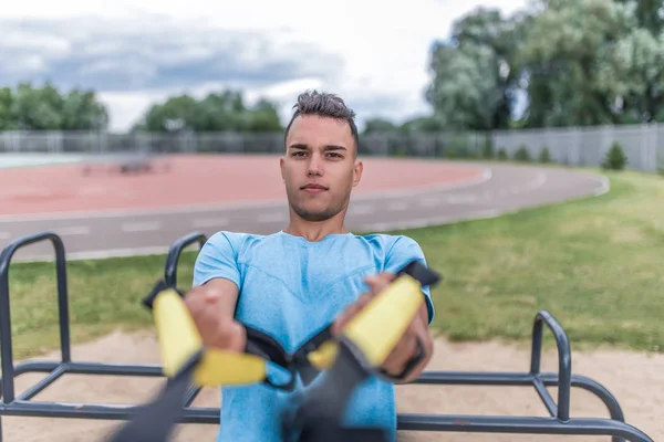 close-up young sports man summer city, pulls up wring out on his hinges, straps horizontal bar, healthy lifestyle fitness workout, concept strength motivation success. Lifestyle young generation.