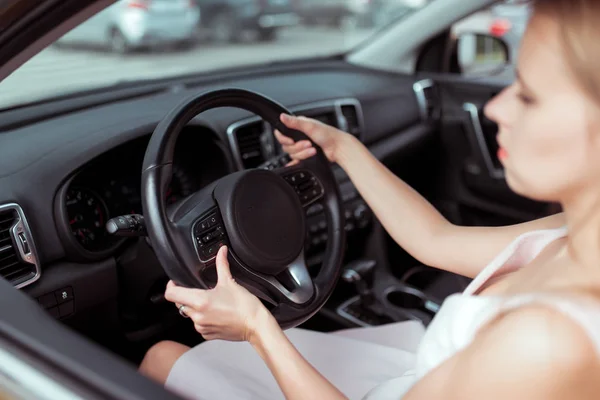 A girl driving a car, in summer city, turns on volume of phone on steering wheel, choice to hang up, talking wirelessly, application in car behind wheel. View of interior car close-up steering wheel. — Stock Fotó