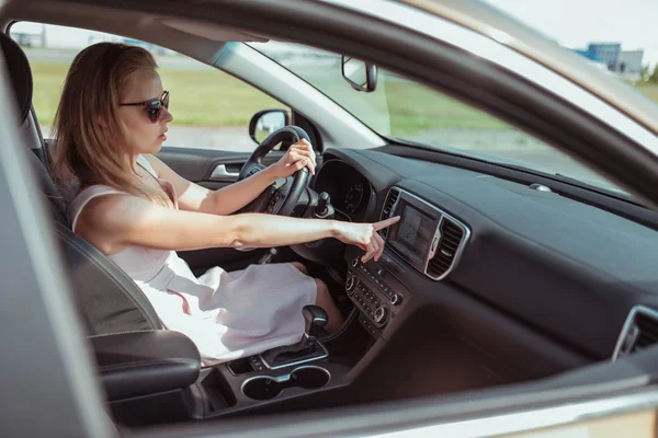 Chica conduciendo un coche, eligiendo la navegación en la pantalla del monitor, presiona el menú táctil, mapa de navegación, selección de ruta, activación de voz en línea, asistente, activación del menú táctil encendido y apagado . — Foto de Stock