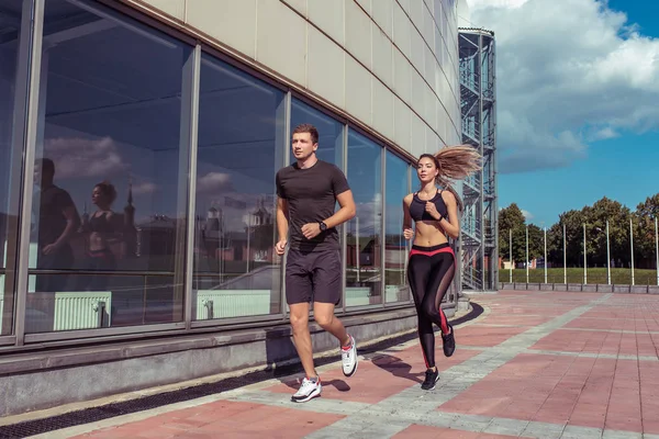 genç çift erkek ve kadın sabah koşu çalıştırmak, aktif yaşam tarzı, spor giyim, şehirde yaz, doğada fitness, arka plan bina cam pencereler, bir spor ilişkisi aile
