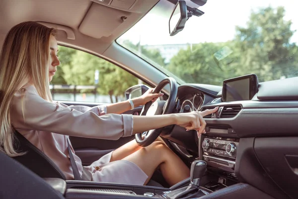 Girl presses the emergency stop button, turning on alarm, activating a problem on the road. Woman driving a car, long hair, in the summer in the passenger compartment. Business lady goes to work. — Stock Photo, Image