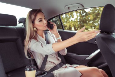 Telefonda konuşuyorum. Taksi şoförü park yeri işaret, iş kadını elinde durdurmak gösterir, arabada oturur, online uygulama akıllı telefon, sıkı pembe takım elbise, uzun saçlı, iş taksi şehir yaz.