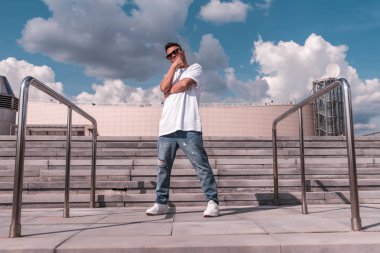 genç adam dansçı, yaz aylarında şehirde merdiven ve binanın arka planda duruyor, breakdanse hareket başlamadan önce poz