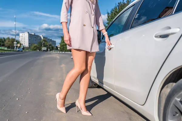 Close-up de uma mulher de negócios, abre a porta de um sedan negócio branco, terno formal bege, sapatos de salto alto, pele bronzeada de uma menina. No verão na cidade . — Fotografia de Stock