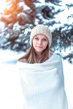 Beyaz şapkalı güzel kış kızı gülümsüyor kış sahiptir. Sıcak bir battaniye, arka plan, kar, kar akıntıları, yeşil Noel ağacı sarılmış. Tatilde bir hafta sonu tatili zevk duyguları.