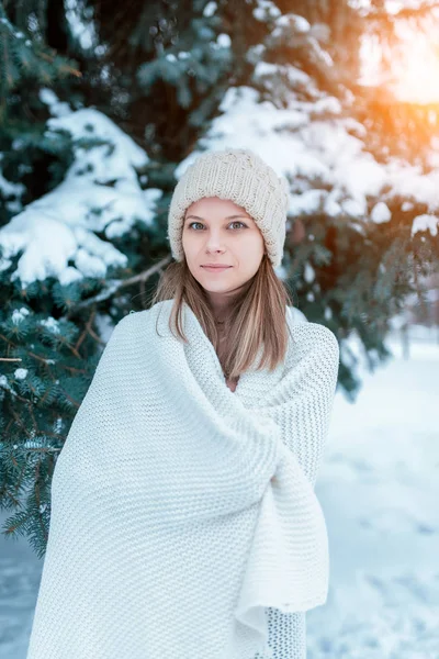 Beautiful and young girl in winter on background of barely snow and snowdrifts. White plaid warm hat, happy smiling hiding behind a warm blanket. Camping in the winter cold season. — Stock Photo, Image