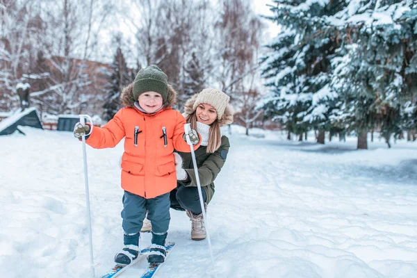 Ibu mengajarkan anak laki-laki berusia 3-5 tahun, sukacita emosi, menyenangkan, tersenyum kebahagiaan, ski di musim dingin, hutan, liburan, resor di taman bersalju, salju latar hanyut pohon. Teks motivasi ruang kosong . — Stok Foto