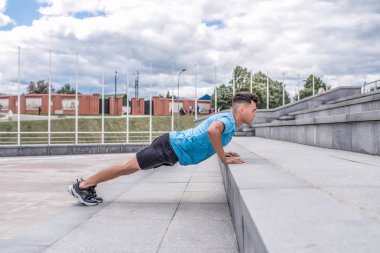 Atletik adam, yaz şehir şınav merdivenlerden, fitness egzersiz, sabah egzersiz açık havada. Spor Ayakkabı Şort. Gençliğin aktif yaşam tarzı.