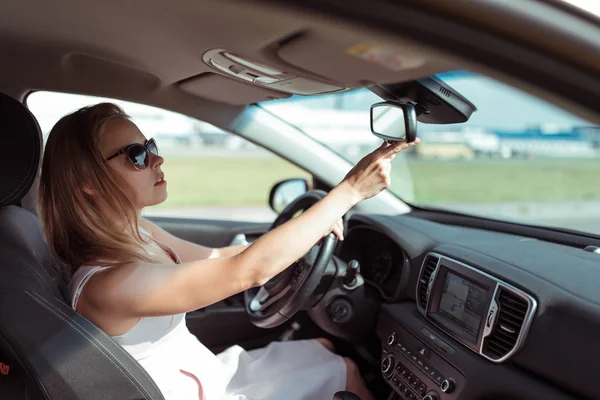 Uma mulher no carro, verifica a fila de trás dos assentos dos passageiros para crianças ou convidados, o espelho da fila traseira e o tipo de assentos, estacionamento retrovisor do carro. Definir um espelho retrovisor . — Fotografia de Stock
