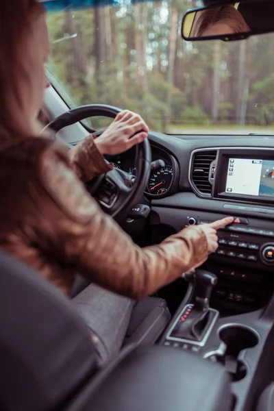 Een vrouw in de auto, drukt op de noodstopknop, in de zomer in het bos, automatische doos, ongeval op de weg, noodstop modus, signalering naar andere auto's. — Stockfoto