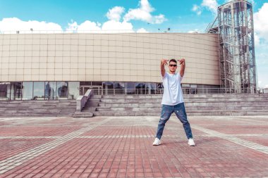 genç şık adam poz ayakta, adam dansçı, yaz şehir, dans break dans, sağlıklı fitness sporcular yaşam tarzı, beyaz t-shirt kot pantolon. Müzikle dans etmek. Halka açık olarak gerçekleştirir. Metin için boş alan.