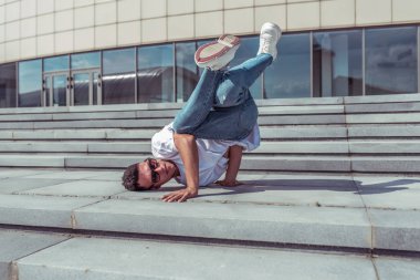 Merdivenlerde Genç şık adam, adam bir dansçı, şehirde yaz aylarında, dans break dans, sağlıklı fitness atlet yaşam tarzı, beyaz t-shirt, kot pantolon, spor ayakkabı. Müzikle dans etmek. Herkese açık olarak gerçekleştirir.
