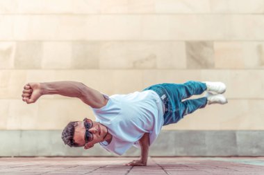 Genç şık atlet arka plan duvar, uçuş süper erkek bir kol, adam dansçı, yaz şehir dans break dans, sağlıklı fitness yaşam tarzı, gömlek kot pantolon. Dans müziği. Herkese açık gerçekleştirir. Boş alan metni.