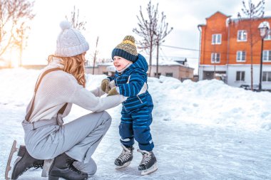 Anne erkek bebek 3-5 yaşında, tren öğrenmek, pist, buz pateni kışın şehirde binmek. Mutlu gülümseyen çocuklar hafta sonu eğlenceli oyun ilk adımlar çocuk buz pateni. Metin için boş alan.