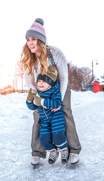Сестра с маленьким племянником, мальчику 3-5 лет, зимний городской каток, веселые катаются, весело играют на природе выходного дня. Обучение катанию на коньках. Зимний снег дрейфует, теплая одежда, шляпы . — стоковое фото