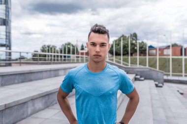 Sporcu pozu, yakın çekim, ciddi bir koç görünüşü, şehirde yaz tatili, spor tişörtü, motivasyon gençlik yaşam tarzı, temiz havada eğitim. Motivasyon aktif yaşam biçimi.
