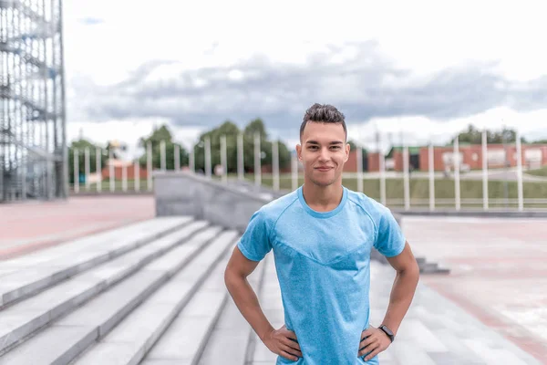 Athlete man smiles, looks attentively, close-up, happy rejoices coach, summer city, sports t-shirt, motivation youth lifestyle, training fresh air. Motivation active lifestyle. Free space for text.
