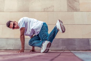 genç adam beyaz bir t-shirt bir dansçı, kot pantolon, şehirde yaz aylarında dans break dans, güneş gözlüğü, beyaz spor ayakkabı arka plan bina bulutlar, aktif hip hop, gençlik yaşam tarzı