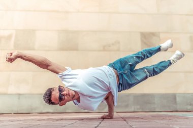 genç adam beyaz bir t-shirt bir dansçı, kot pantolon, şehirde yaz aylarında dans break dans, güneş gözlüğü, beyaz spor ayakkabı arka plan bina bulutlar, aktif hip hop, gençlik yaşam tarzı