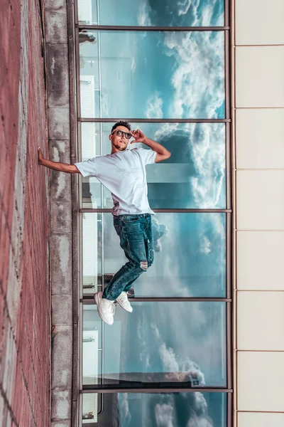 genç adam beyaz bir t-shirt bir dansçı, kot pantolon, şehirde yaz aylarında dans break dans, güneş gözlüğü, beyaz spor ayakkabı arka plan bina bulutlar, aktif hip hop, gençlik yaşam tarzı
