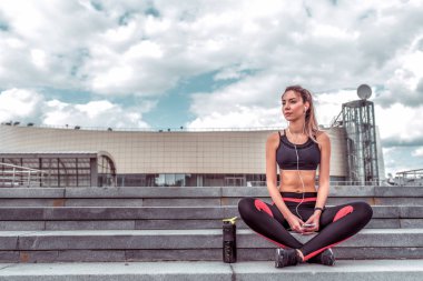 Spor giyim sektöründe güzel bir kız, yaz şehri temiz havada sıkı bir eğitim alıyor, kulaklıkla müzik dinliyor, mesafeye bakıyor, mesajlaşmak için boş alan arıyor. Oturma adımları arka planı bulutlandırır.