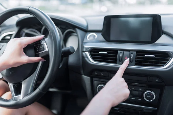 A közeli női ujj tartalmazza a vészleállító gombot, a riasztót, a problémát és a balesetet, a méretjelző jelzést, a közúti biztonság aktiválását. Autós belső tér, érintőképernyős kijelző. — Stock Fotó