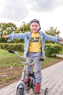 little boy, child of 3-5 years old, happy to ride bicycle, summer spring autumn day in city park, keeps his balance, rests on weekends, learns to ride bicycle training and dexterity.