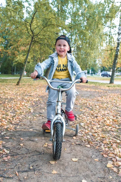 Anak kecil, anak berusia 3-5 tahun, tersenyum bahagia, tertawa, naik sepeda, pada musim semi hari di taman kota, menjaga keseimbangan, beristirahat pada akhir pekan, belajar untuk naik sepeda pelatihan dan ketangkasan . — Stok Foto