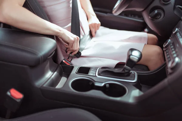 Close-up, uma menina de vestido rosa no interior do carro prende seu cinto de segurança, interior da caixa de velocidades automática do carro, braço, segurança no carro, ativação de airbags do carro . — Fotografia de Stock