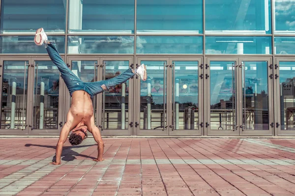 Erkek sporcu, dansçı yazı. Amuda kalkma, boş alan motivasyon metni. Arka plandaki cam pencereler. Modern break dans tarzı hızlı, fitness sporu hip hop hareketli. Şehir kültürü, sokak.