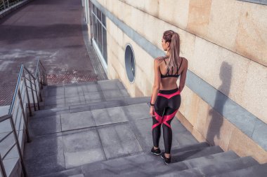 Kız atlet, spor kadın merdivenleri, arkadan manzara, yaz, sonbahar baharı şehirde, motivasyon metni, spor giyim, spor ayakkabıları, spor ayakkabıları, spor ayakkabıları, aktif fitness yaşam tarzı, açık hava sporu için boş alan..