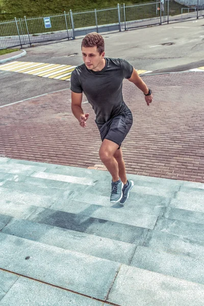 Чоловік спортсмен, влітку він біжить по сходах міста, активний спосіб життя, мотивація займатися фітнесом, спортивним одягом, футболкою, шортами та кросівками . — стокове фото